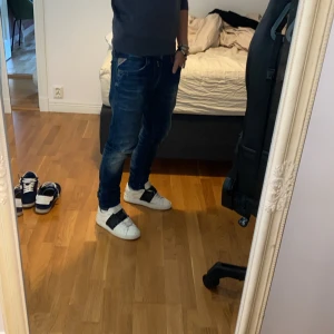 Valentino Rockstud Open sneakers vit/svart - Säljer ett par feta Valentino Rockstud Open sneakers i vitt skinn med bred svart rem och ikoniska nitar. Klassisk rund tå, snörning och chunky platt sula. Perfekta för dig som vill sticka ut med lyxig streetstyle.