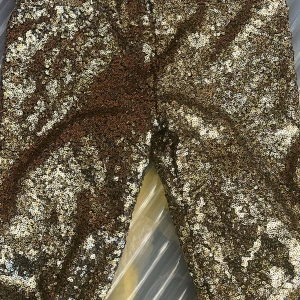 Guldglittriga paljettbyxor - Säljer ett par riktigt snygga byxor täckta med glittrande guldpaljetter. Perfekta för dig som vill sticka ut och glänsa. Byxorna har en rak passform och är tillverkade i ett syntetmaterial som ger extra komfort och glans. Det är till barn i strl 146/152