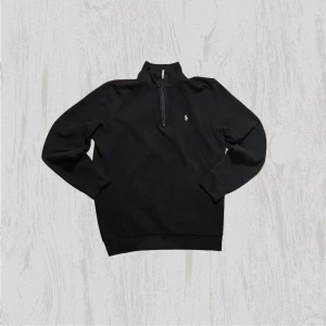 Svart half zip tröja från Ralph Lauren - Svart långärmad tröja från Ralph Lauren med half zip och klassisk ståkrage. Tröjan har en liten broderad logga på bröstet och är tillverkad i mjuk bomull. Perfekt för en stilren och avslappnad look.