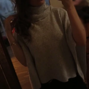 Grå poncho från Kappahl - Jag säljer en grå poncho från Kappahl med en polo krage och en lös passform. Tröjan är ribbstickad och har ett snyggt fall över axlarna, perfekt för lager på lager. Materialet är mjukt och stickat, passar dig som gillar oversized vibes. Den är väldigt bekväm, säljer för att jag aldrig använder den. Original pris, prislappen är på❤️
