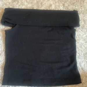 Svart off shoulder från UNIQ STUDIO - Svart off shoulder topp från UNIQ STUDIO. Toppen är ärmlös och har en tight passform som sitter snyggt mot kroppen. Materialet är mjukt , perfekt för att skapa en clean look. Passar dig som gillar minimalistisk stil.