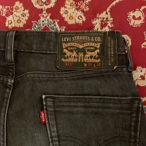 Levi's 511 svarta jeans W30 L32 - Säljer ett par svarta Levi's 511 jeans i slim fit med klassisk femficksdesign. Jeansen har raka ben, normal midja och är tillverkade i ett mjukt denimtyg med stretch. Perfekta för dig som gillar en stilren och enkel look.