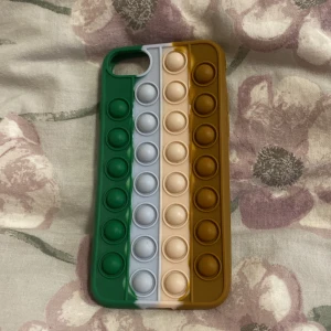 Pop It Fidget Skal till iPhone SE/7/8 - Färgglatt Pop It-skal till iPhone SE/7 . Tillverkat i mjuk silikon med integrerade poppande bubblor för stresslindring och skydd. Skalet är i mycket gott skick utan synligt slitage eller defekter. Perfekt för dig som vill kombinera skydd och lekfull design.