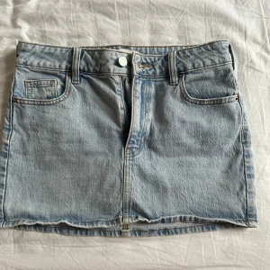 Ljusblå jeanskjol från Pacsun - Säljer en ljusblå jeanskjol från Pacsun med klassisk femficksdesign, bälteshällor och knappstängning framtill. Kjolen har raka linjer och en enkel, stilren look som passar perfekt till sneakers eller boots. Använt en gång.