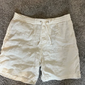 Vita linneshorts med snörning på Zara - Fräscha vita shorts från Zara i mjukt linne, med elastisk midja och snörning framtill. De har en clean look med raka ben och två fickor bak. Perfekta för chill dagar när du vill ha en enkel och stilren vibe.