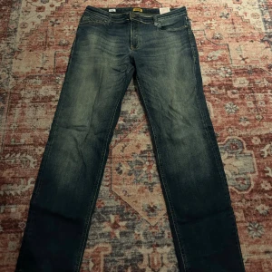  jeans från Jack & Jones - Snygga mörkblå jeans från Jack & Jones med klassisk femficksdesign och diskret slitning framtill och baktill. Jeansen har raka ben och normal passform, perfekt för en avslappnad stil. Tillverkade i mjukt denimtyg för skön känsla hela dagen.