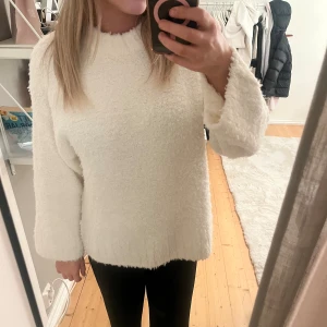 Vit fluffig tröja från H&M - Supermysig vit tröja från Hm i storlek M. Den har en fluffig, stickad yta och en rak, loose passform med långa ärmar och rund hals. Perfekt för att hålla sig varm och se chill ut under höst och vinter.