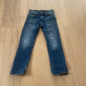 Blå jeans från Replay straight fit - Snygga blå jeans från Replay med klassisk femficksdesign och raka ben. Jeansen har tydliga slitningar och kontrastsömmar, samt Replay-logga på fickan och läderpatch bak i midjan. Passformen är straight och materialet är robust denim.