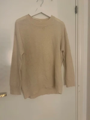 Beige stickad tröja från 157 - Säljer en beige stickad tröja från 157 i storlek M. Tröjan har rund hals, ribbade muddar och lång ärm. Perfekt för dig som gillar enkel och clean stil. Materialet är mjukt och skönt, passar bra till jeans eller kjol.