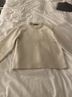 Beige stickad tröja Gina Tricot XS - Säljer en enkel och snygg beige stickad tröja från Gina Tricot i storlek XS. Tröjan har rund halsringning, ribbade muddar och lång ärm. Perfekt till höst och vinter för en clean och stilren look.