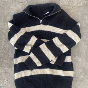 Randig stickad tröja från Zara - Säljer en svart och beige randig stickad tröja från Zara i storlek M. Den är stor o varm så den är perfekt för vintern. Zara märket har släppts på ena sidanvid nacken. Hör av er vid frågor✅