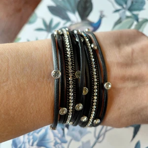 Svart wrap-armband med strass - Snyggt nytt svart wrap-armband med flera tunna band och glittriga strassdetaljer. Armbandet har silverfärgade stenar som ger extra bling och är perfekt för dig som gillar att sticka ut. Lätt att matcha med andra smycken och ger en cool vibe till din outfit. Mitt Pris: 100:-
