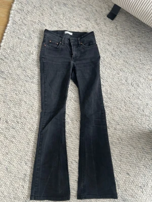 Svarta bootcut jeans strl 34 - Säljer ett par svarta bootcut jeans från Gina (Perfect Jeans i storlek 34). Jeansen har klassisk femficksdesign, knapp och dragkedja framtill samt bälteshällor. Materialet är jeans med en mörk tvätt och lätt stretch för skön passform.