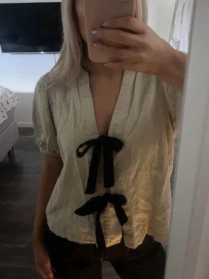 Topp från Zara - Säljer denna fina blusen från zara! Den är beige med svarta rosetter! Den har knappt används och är som ny💕