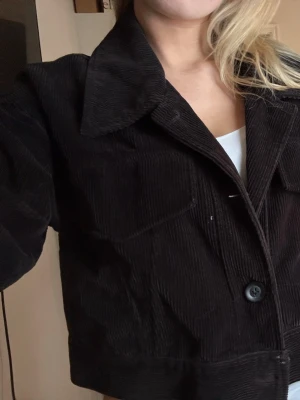 Svart manchesterjacka  - Säljer en svart manchesterjacka. Jackan är croppad och har stora knappar framtill samt på ärmsluten. Perfekt till lager på lager och ger en cool, avslappnad vibe.