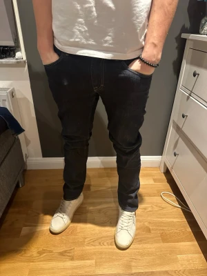 Mörkblå tiger of Sweden jeans - Säljer ett par mörkblå jeans från tiger of Sweden i modellen Iggy Klassisk femficksdesign med kontrastsömmar och rak passform. Jeansen är tillverkade i ett slitstarkt jeansmaterial. 