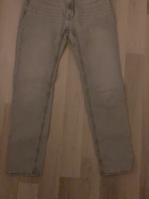 Grå jeans från Dressmann 29/32 - Säljer ett par grå jeans från Dressmann i storlek 29/32. Byxorna har klassisk femficksdesign, raka ben och kontrastsömmar. Materialet är jeans och färgen är ljusgrå. Perfekta till en avslappnad stil.