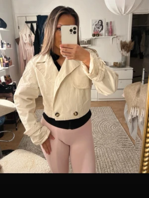 Beige trenchcoat  - Säljer min Snygga croppade trenchcoat i beige, stora dekorativa knappar och detaljer. Super fin att ha nu till hösten 