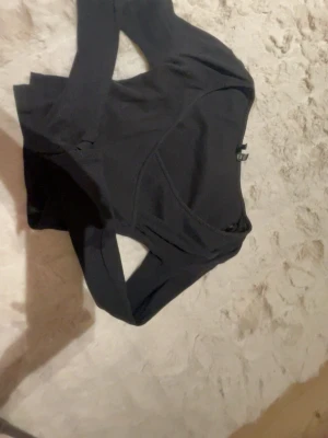 Svart croppad topp från Vero Moda - Säljer en svart croppad långärmad topp från Vero Moda i ribbad bomull. Toppen har en snygg v-ringning och sitter tight på kroppen, perfekt till höga jeans eller kjol. Enkel och stilren design som är lätt att matcha.