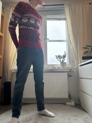 Röd jultröja med tomtar och text - Säljer en röd jultröja med mönster av tomtar, granar och snöflingor samt texten 'XMAS SWEET' och 'HO HO HO' över bröstet. Tröjan har rund halsringning och långa ärmar. Perfekt för att maxa julstämningen!