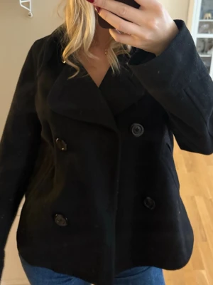 Svart skepparkavaj med knappar - Säljer en klassisk svart skepparkavaj med dubbelknäppning och bred krage. Gammal modell från HM. Passar M