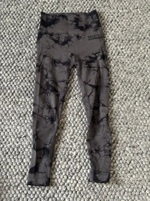 Grå-svarta Better Bodies leggings - Säljer ett par grå leggings från Better Bodies med svart batikmönster. De är högmidjade och har en tight passform som sitter skönt vid träning. Materialet är stretchigt och mjukt, perfekt för gymmet eller yoga.