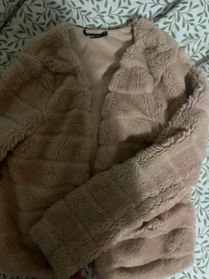 Beigerosa teddyjacka från Gina Tricot XS - Supermjuk och fluffig teddyjacka i beige från Gina Tricot. Jackan har lång ärm, öppen framtill och är i en oversized modell. Perfekt för dig som vill ha en mysig och trendig look under höst och vinter.