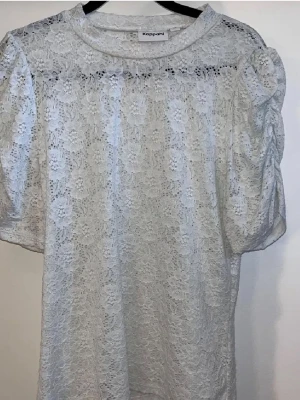 Vit spetsblus från Kappahl - Säljer en vit blus från Kappahl i storlek M. Den har blommigt mönster och har puffiga korta ärmar. 