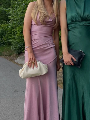 Ljusrosa balklänning  - Säljer min superfina ljusrosa balklänning med smala axelband och draperad detalj i midjan. Klänningen har en lätt glansig finish och v-ringad halsringning. Perfekt för bal eller student! Materialet känns mjukt och följsamt. Storleken är som en xs/s🩷