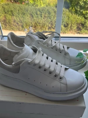 Vita sneakers, Alexander McQueen - Säljer min killes vita snygga  Alexander McQueen sneakers. Dem är knappt använda och är i väldigt bra skick! (Skorna kommer med original box)