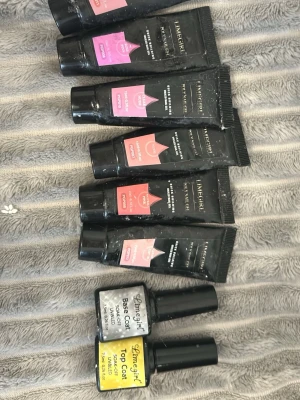 Limegirl Poly Nail Gel Set - Säljer ett set med Limegirl Poly Nail Gel i flera rosa och nude nyanser, perfekt för att bygga snygga naglar hemma. Inkluderar även Base Coat och Top Coat i flaskor. Tuben är svart med färgmarkering och flaskorna har tydliga etiketter.