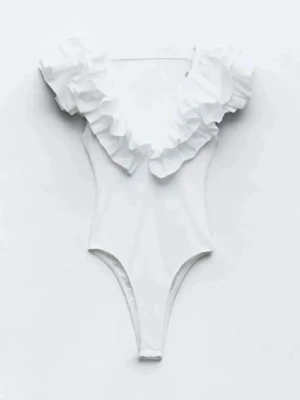 Vit volangväst med djup v-ringning - Säljer en vit väst med djup v-ringning och stora volangdetaljer längs axlar och halsringning. Västen är figurnära och har en modern, feminin look som sticker ut. Perfekt att styla över en topp eller som den är för en trendig outfit.