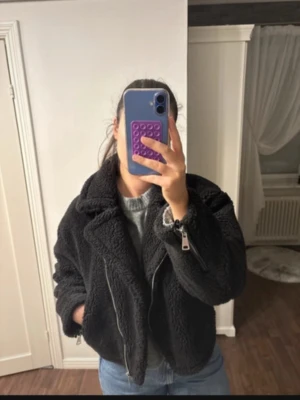 Svart teddyjacka - Supersnygg svart teddyjacka från NA-KD i lätt croppad modell som ger en cool och modern look. Mjuk och varm med stilrena silverdetaljer som verkligen lyfter outfiten. Köpte den k october secondhand, men har inte kommit till användning. Bilder är från förra ägaren! Priset går att diskutera🥰🥰  