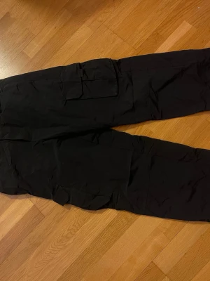 Svarta cargopants från New Look - Säljer ett par svarta cargopants från New Look med flera stora fickor på sidorna. Byxorna har rak passform och är tillverkade i ett lätt bomullsmaterial. Perfekta för dig som gillar streetwear och vill ha en avslappnad look.
