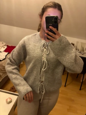 Grå stickad kofta med snörning - Mysig grå stickad kofta med breda ärmar och snygg snörning framtill. Perfekt för lager-på-lager och chill dagar. Koftan har en rak passform och är ribbstickad för extra struktur. Ull mix!  Knappt använd!