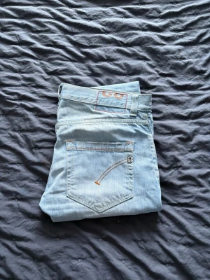 Ljusblå DonDup jeans - Säljer ett par ljusblå DonDup jeans. Jeansen har raka ben, orangea sömmar och en snygg detalj på bakfickan. Tillverkade i mjukt jeanstyg som är skönt att bära. Perfekta för dig som gillar en avslappnad stil och vill ha stil. Vid snabb affär kan vi gå ner i pris 😊