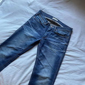 Acne Studios Jeans – Mörkblå Slim/Straight - Acne Studios Jeans – Slim Straight Säljer ett par snygga Acne Studios-jeans i mörkblå denim med stilrena fades som ger den där perfekta vintage-looken. 	•	Midjemått: 39 cm 	•	Längd: 103 cm 	•	Passform: Slim Straight 	•	Mjukt, bekvämt material med hög kvalitet som Acne alltid levererar. St 30/32  Perfekta både till vardags och för en mer uppklädd stil. Väldigt fint skick och redo för ett nytt hem!