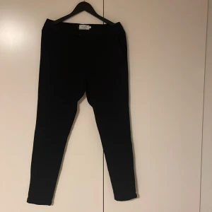Svarta kostymbyxor från Les Deux - Snygga svarta kostymbyxor från Les Deux, modell Como Suit Pants. Byxorna har smal passform, bälteshällor och knäppning fram. Materialet är en mix av polyester, viskos och elastan vilket ger en skön stretch och stilren look.  Använd fåtal gånger, tar emot prisförslag!                Nypris 1199kr