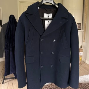 Mörkblå skepparkavaj Selected Homme - Marinblå skepparkavaj från Selected Homme med dubbelknäppning. Fyra fickor framtill och är helfodrad. Ullblandning så väldigt varm. Skriv om ni undrar något 🤝