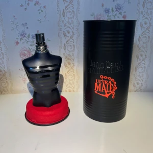Jean Paul Gaultier Ultra Male 125ml - Jean Paul Gaultier Ultra Male Eau de Toilette Intense i en ikonisk svart flaska formad som en manlig torso med silverdetaljer. Kommer i en svart metallcylinder med röd logga. Volymen är 125 ml. En maskulin och modern doft med snygg design.