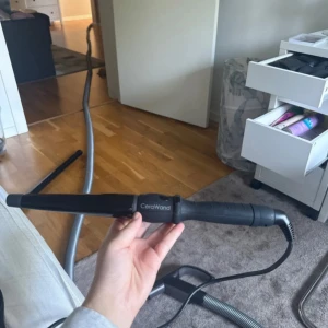 CeraWand svart locktång - Säljer en svart locktång från CeraWand med konformad keramisk stav och ergonomiskt handtag. Perfekt för att skapa snygga lockar och waves. Sladden är lång och roterbar för smidig styling. Passar dig som vill ha ett proffsigt resultat hemma.