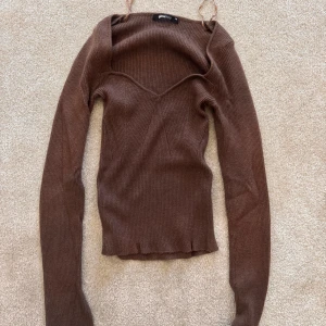 Brun ribbad långärmad tröja Gina Tricot - Säljer en brun ribbad långärmad tröja från Gina Tricot i storlek XS. Tröjan har en snygg v-ringad halsringning  med långa ärmar. Perfekt att styla med jeans eller kjol! 