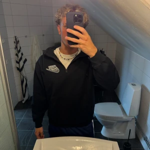 Nike x Supreme svart hoodie M - Svart hoodie från Nike x Supreme med broderad Nike-logga på bröstet och Supreme-tryck på huvan. Half zip-dragkedja framtill och stor huva. Mjuk fleece på insidan för extra komfort. Perfekt för dig som gillar streetwear och vill sticka ut.