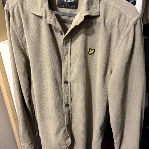 Skjorta/overshirt från lyle & scott - Snygg beige skjorta i manchester från Lyle & Scott med klassisk krage och svarta knappar. Storlek S. Går att använda som tunnare overshirt men även som skjorta.