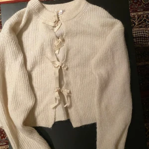 Beige stickad kofta med knytband - Från Gina fin stickad me rosetter 