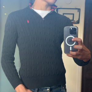 Svart cable knit (stickad) ralph lauren 1/4 zip - •Färg: Mörkblå med röd logga  •Modell: Halvzip med kabelstickat mönster  •Material: Bomull (100%) – mjuk och bekväm.  •Storlek: L (barn/ungdom, motsvarar ca 14–16 år, se mått) och han på bilden är ca 178cm  •Skick: Mycket fint, sparsamt använd, inga fläckar eller hål  Perfekt klassisk tröja från Ralph Lauren som passar till allt 👌  Kolla gärna in profilen, det finns flertalet märkeskläder och skor. Du kommer säkerligen hitta något mer intressant 😉💯  Mått: -Längd = 57cm -Bredd = 44cm