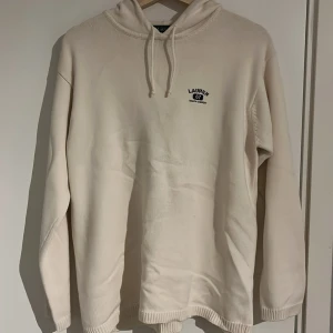 Beige stickad hoodie från Ralph Lauren - Snygg beige hoodie från Ralph Lauren med broderad logga på bröstet. Tröjan är i 100% bomull, har huva med snörning och långa ärmar. Perfekt för dig som gillar en clean och stilren look med premiumkänsla.