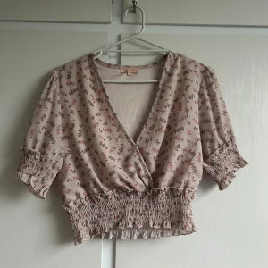 Blommig omlottopp med volang - M men passer en S