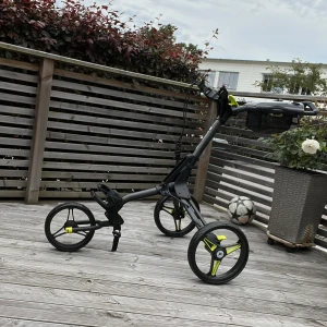 Svart golfvagn Motocaddy Cube - Säljer en svart golfvagn Motocaddy Cube med tre hjul och detaljer i gult. Perfekt för att rulla runt golfbagen på banan. Smidig och lätt att fälla ihop, med praktiska hållare och robust ram i syntetmaterial.