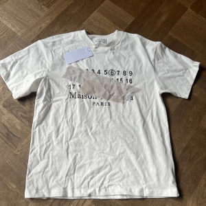 Maison Margiela vit t-shirt med print - Helt ny maison margiela t shirt i storlek S. men den är väldigt stor i storleken så skulle mer säga att det är en M. 1850kr om du köper den här och min andra maison margiela t shirt på min profil!